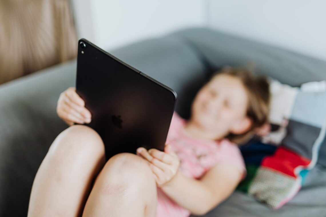 girl lying on a couch using a tablet