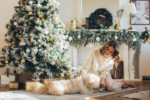 woman in white sweater sitting beside white dog