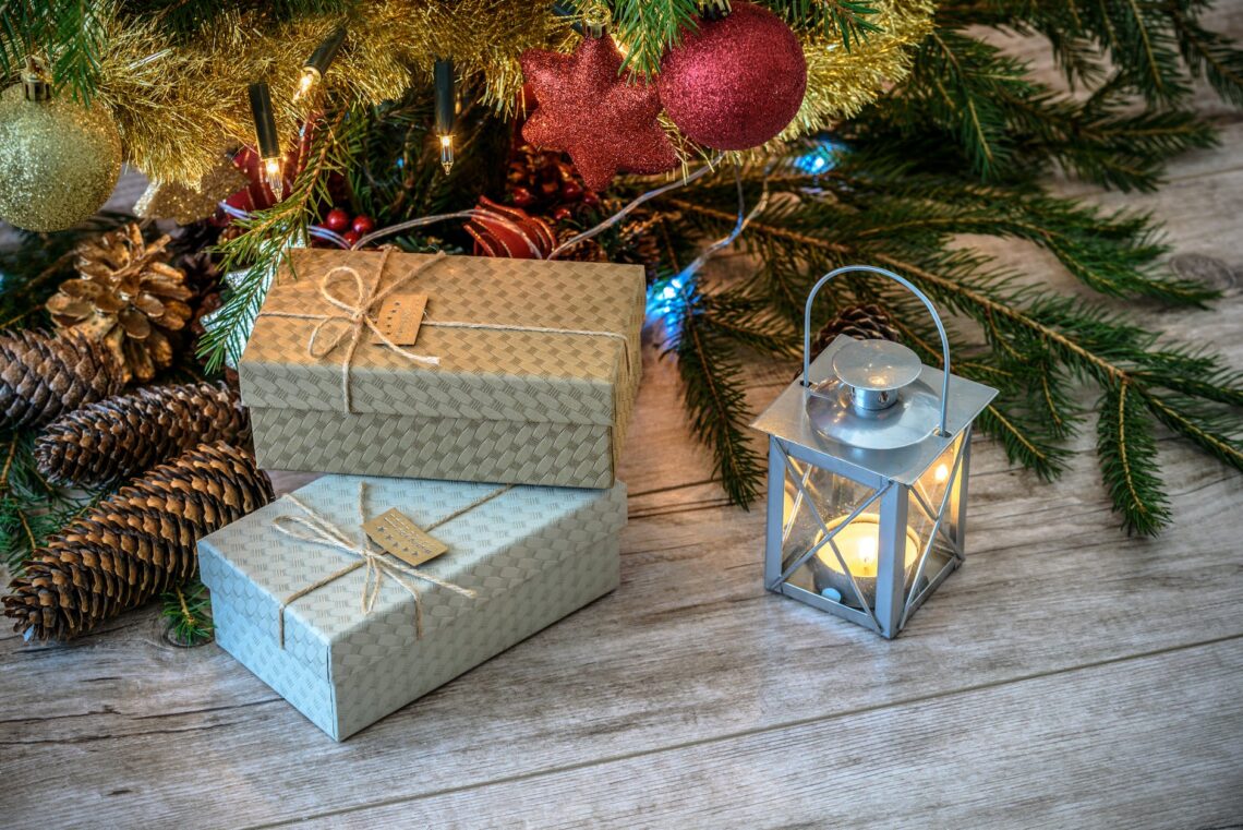lit candle inside lantern beside gift boxes and christmas tree