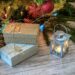 lit candle inside lantern beside gift boxes and christmas tree