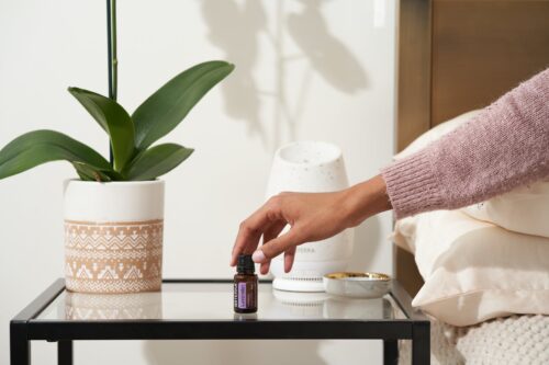 a hand putting the essential oil bottle on the bedside table